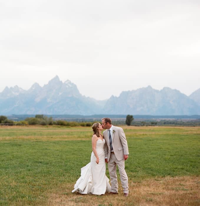 A bride and groom kissing in front of the Grand Teton mountain range in Grand Teton National Park.